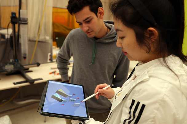 Two students look at design elements on an iPad