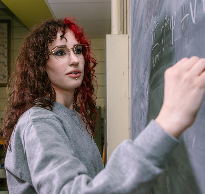 Kira Richards works out a physics formula on a chalkboard.