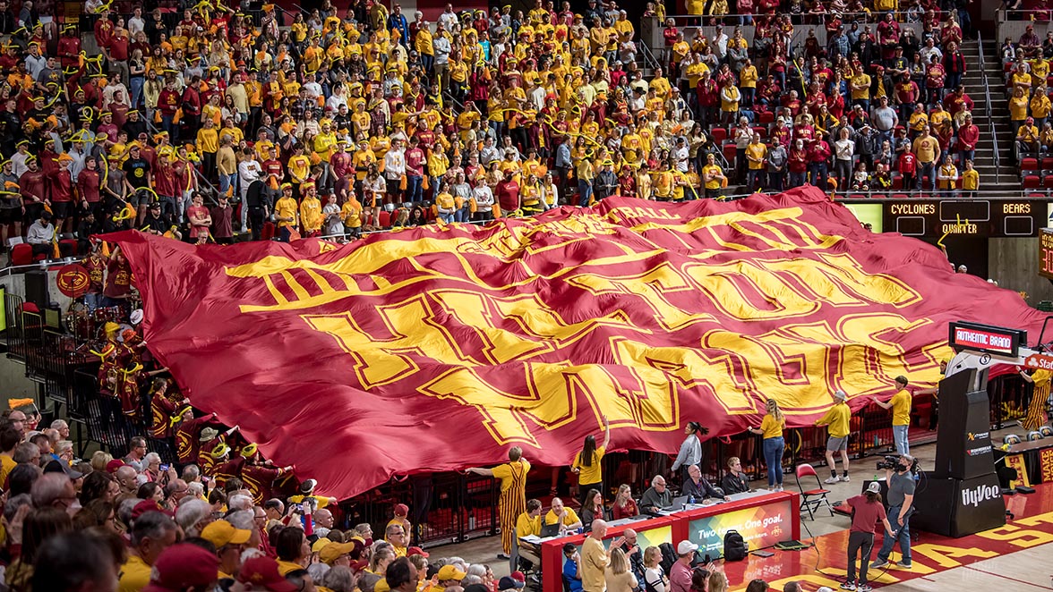 The student section covered by a giant Hilton Magic flag at a basketball game