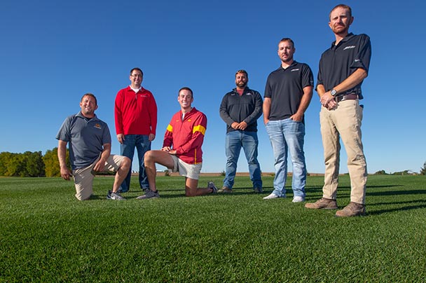 A group of students pose on the turfgrass grown for the ISU football field
