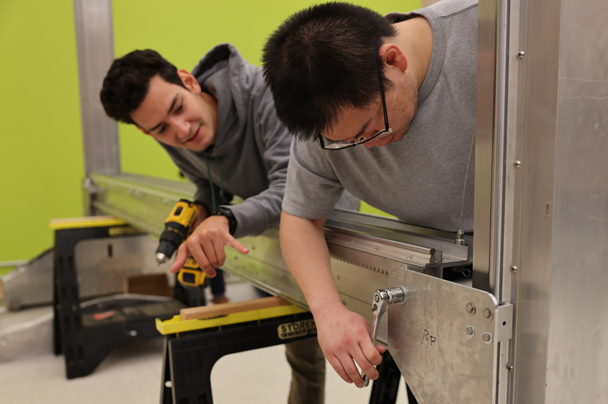 Two students work on constructing a metal support