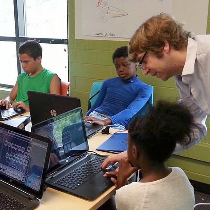 Christopher Whitmer working on game-based STEM tools with children in a classroom