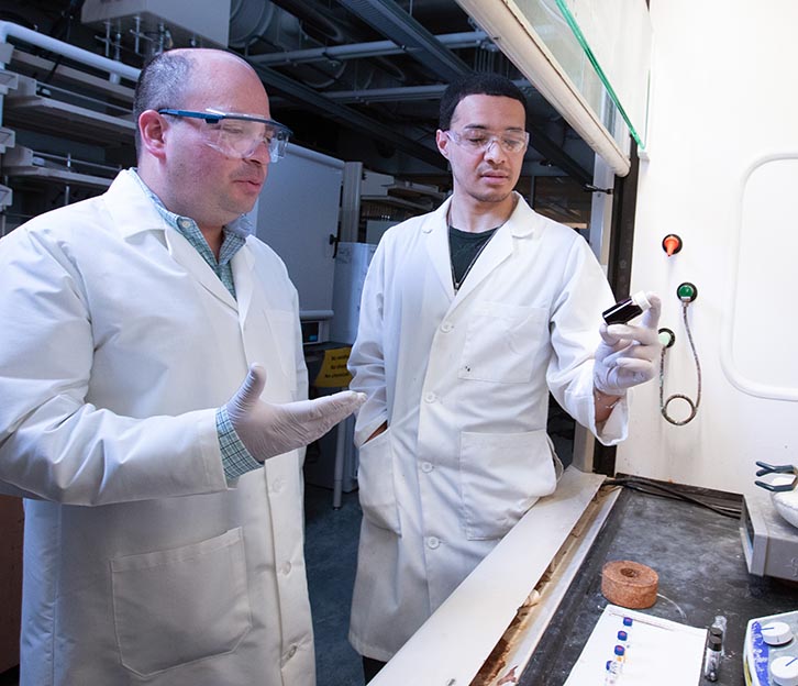 Javier Vela and another researcher examine a liquid in a lab setting