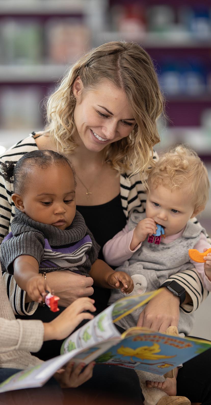 Shot of a young adult reading with two small children