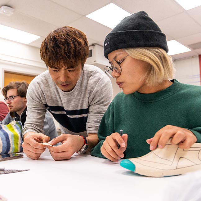 A student and instructor work on a shoe design