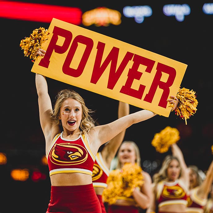 Dance squad member holds a "power" sign above her head during a game