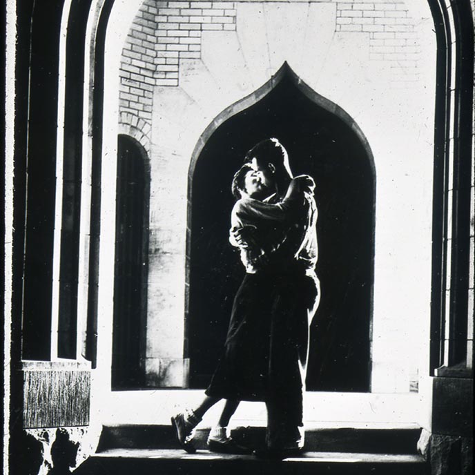 Archived black and white photo of a couple kissing under the campanile