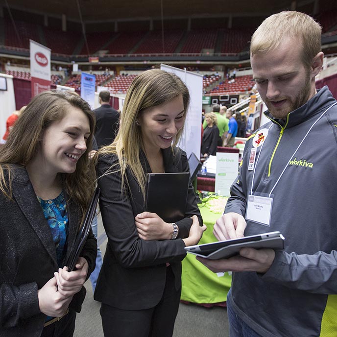 Two students talk with a Workiva company recruiter at a career fair