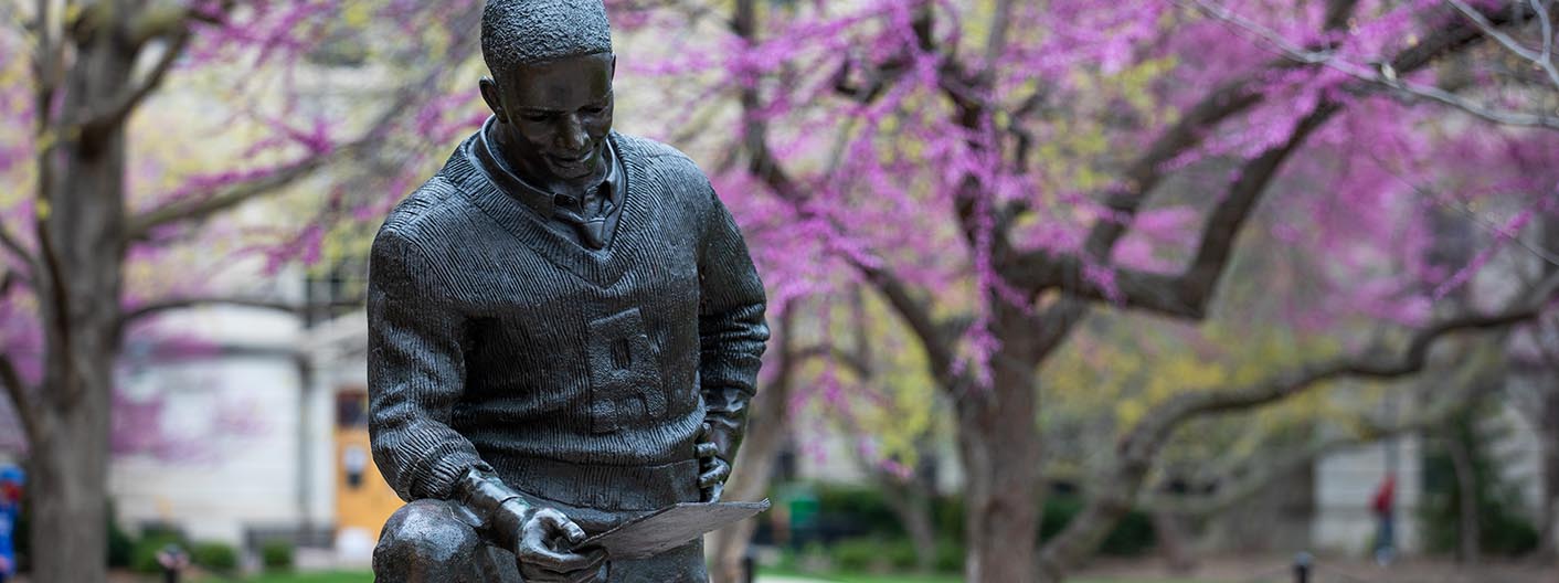 Closeup of the Jack Trice sculpture with redbud trees blooming on a spring day