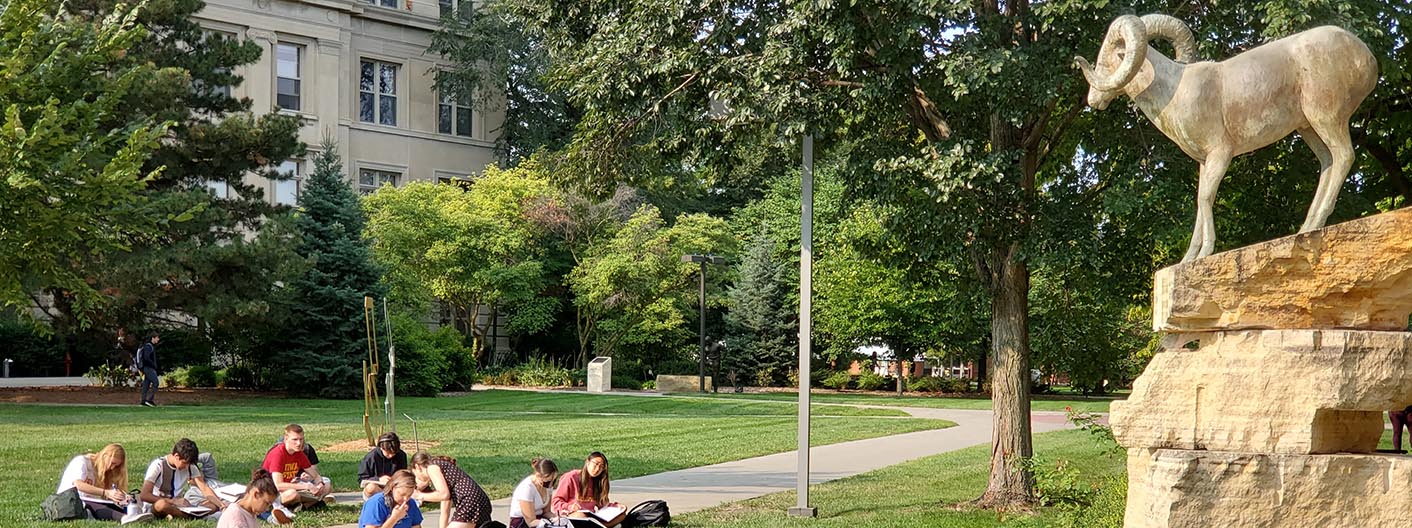 Students sit on the ground and sketch the Bighorn sculpture