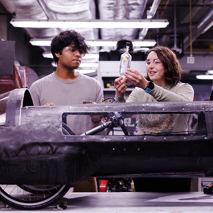 Two students work on a mechanical engineering vehicle