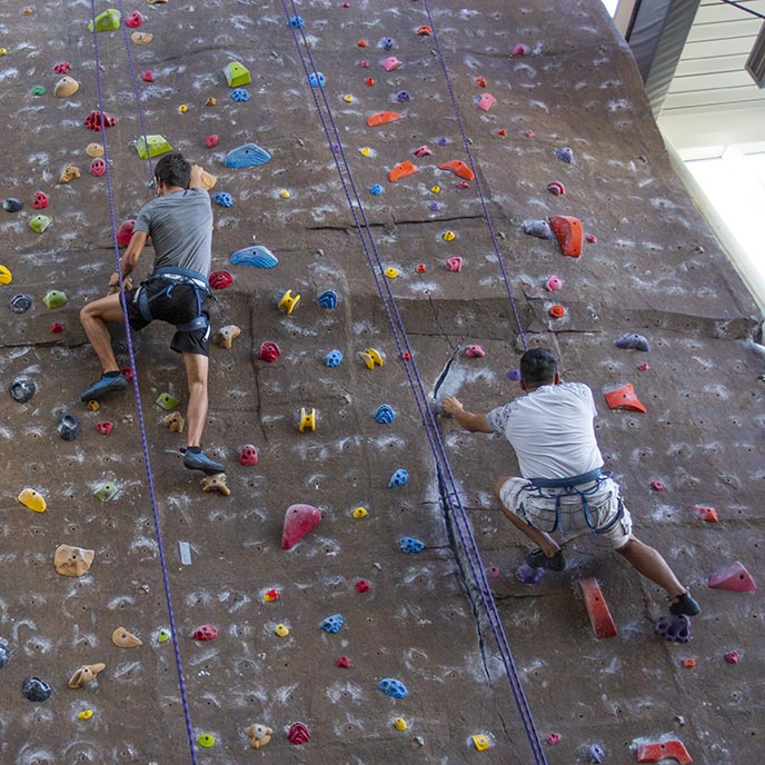 Two students scale the climbing wall in State Gym