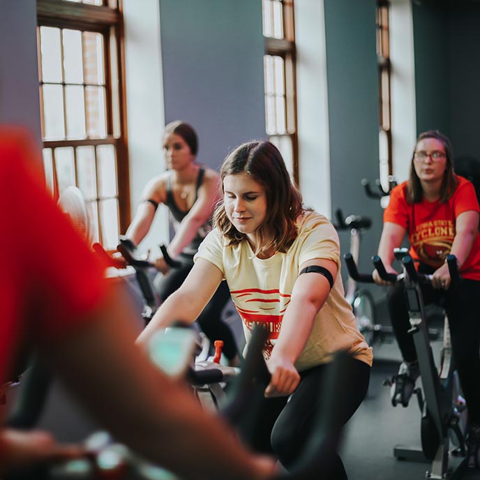 Three people ride stationary bikes during a Rec Services workout