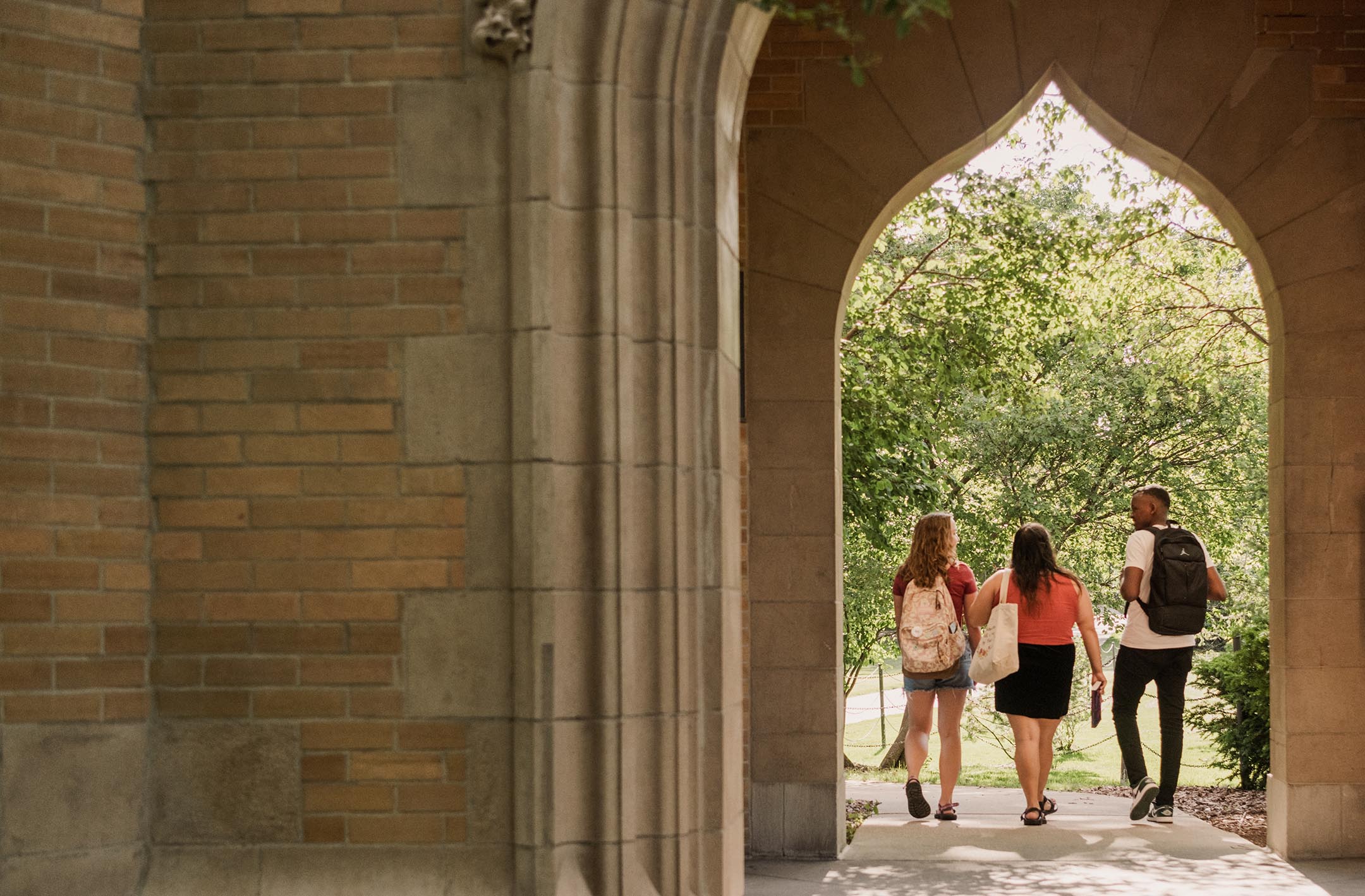 View from behind of three students walking through the Campanile's arched passageway