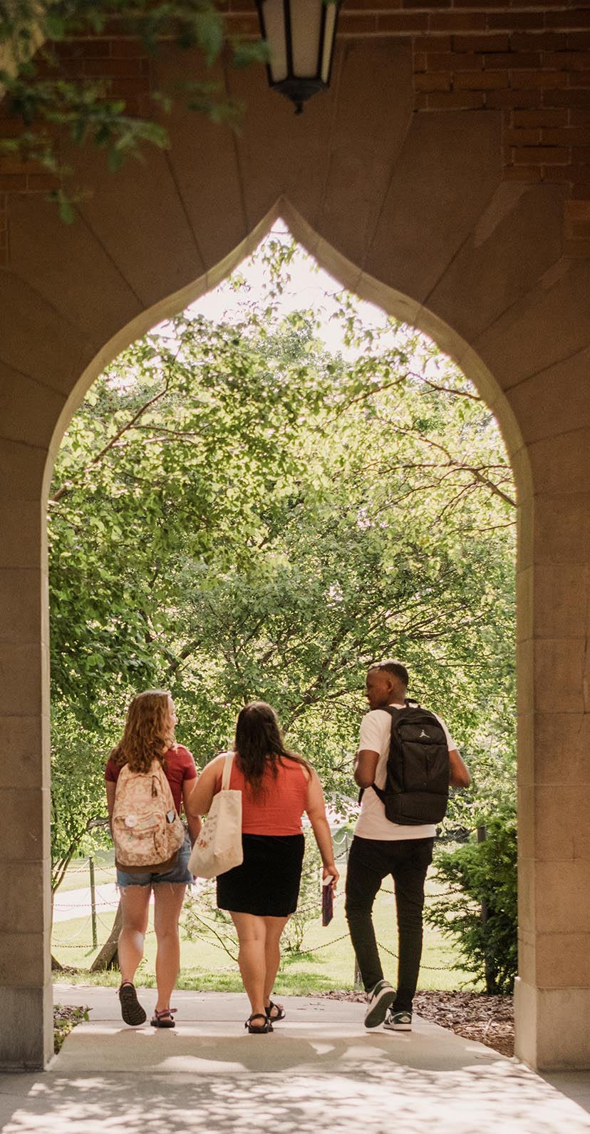 View from behind of three students walking through the Campanile's arched passageway