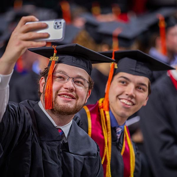 Two students take a selfie at graduation