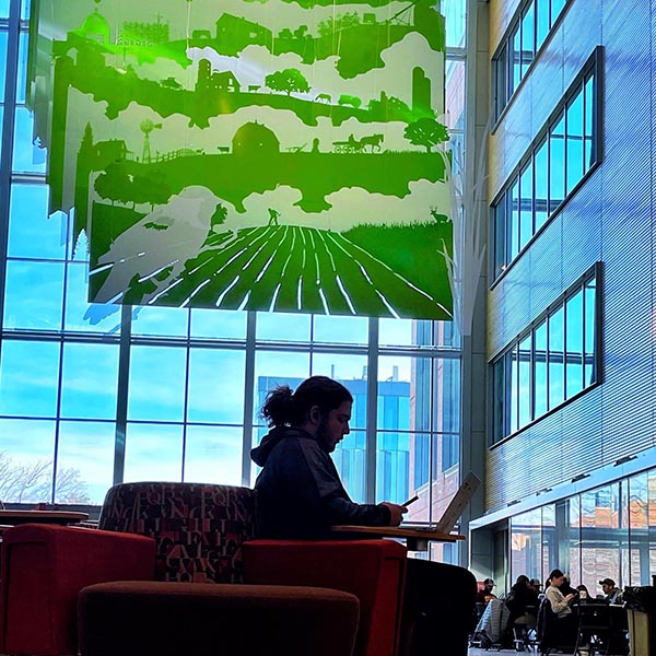 Silhouette of a student studying in the Sukup Building atrium.