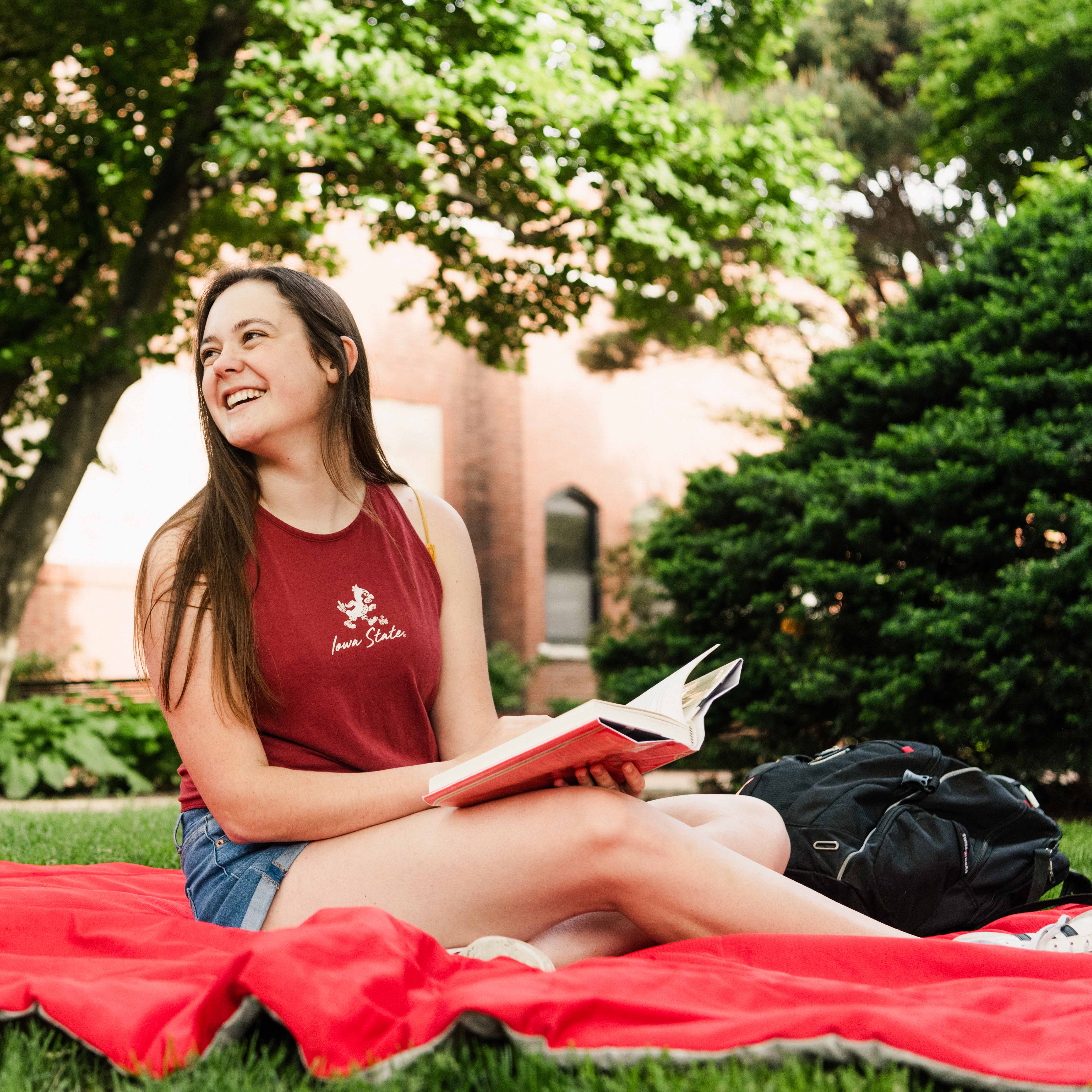 Student reading a book on the grass