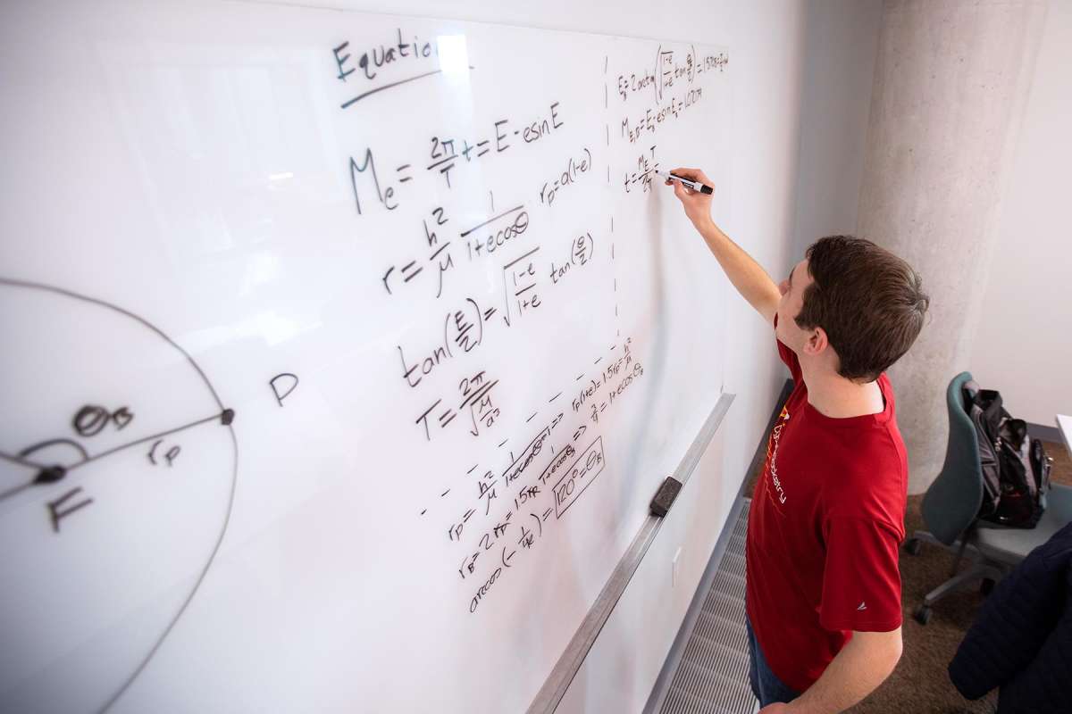 A student writing equations on a whiteboard