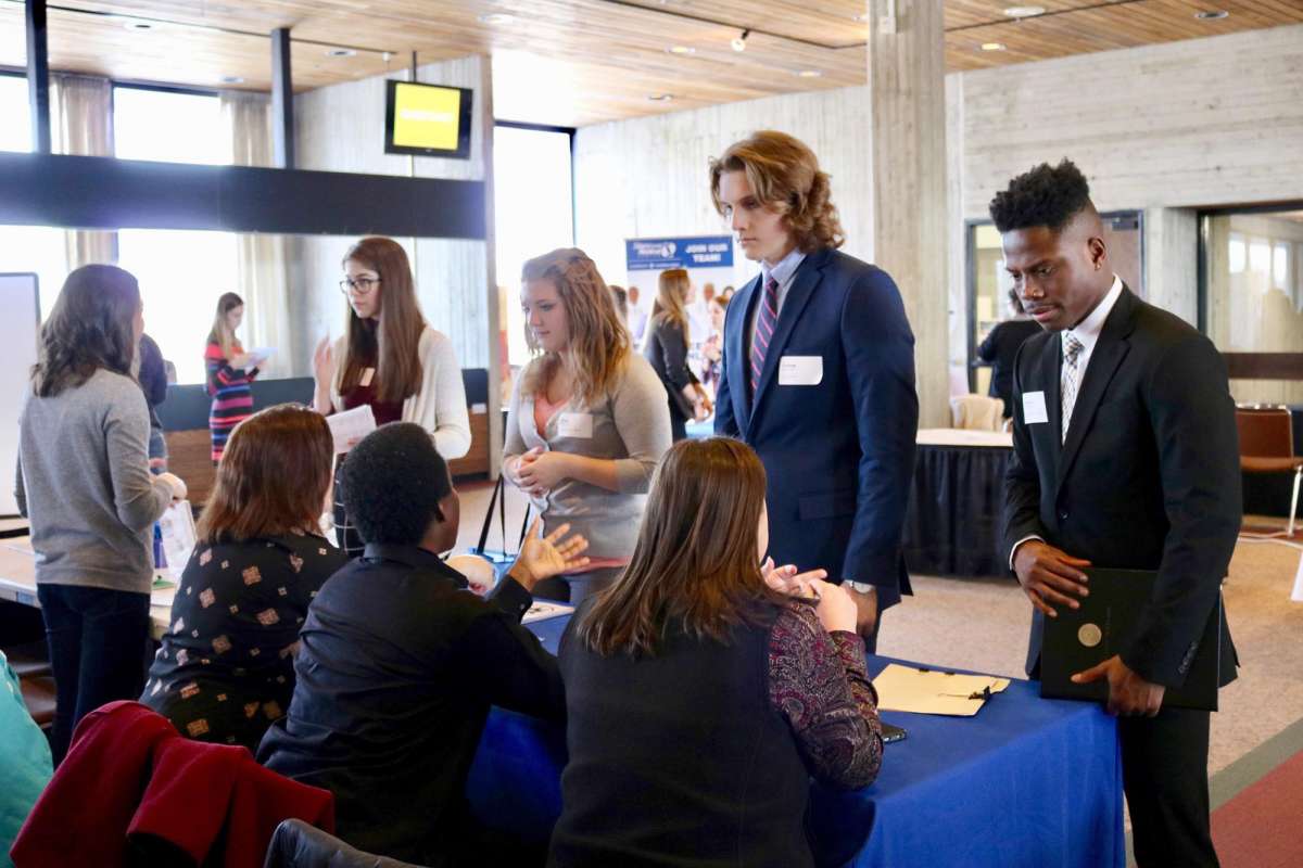 Four students meet with potential employers at a career fair table