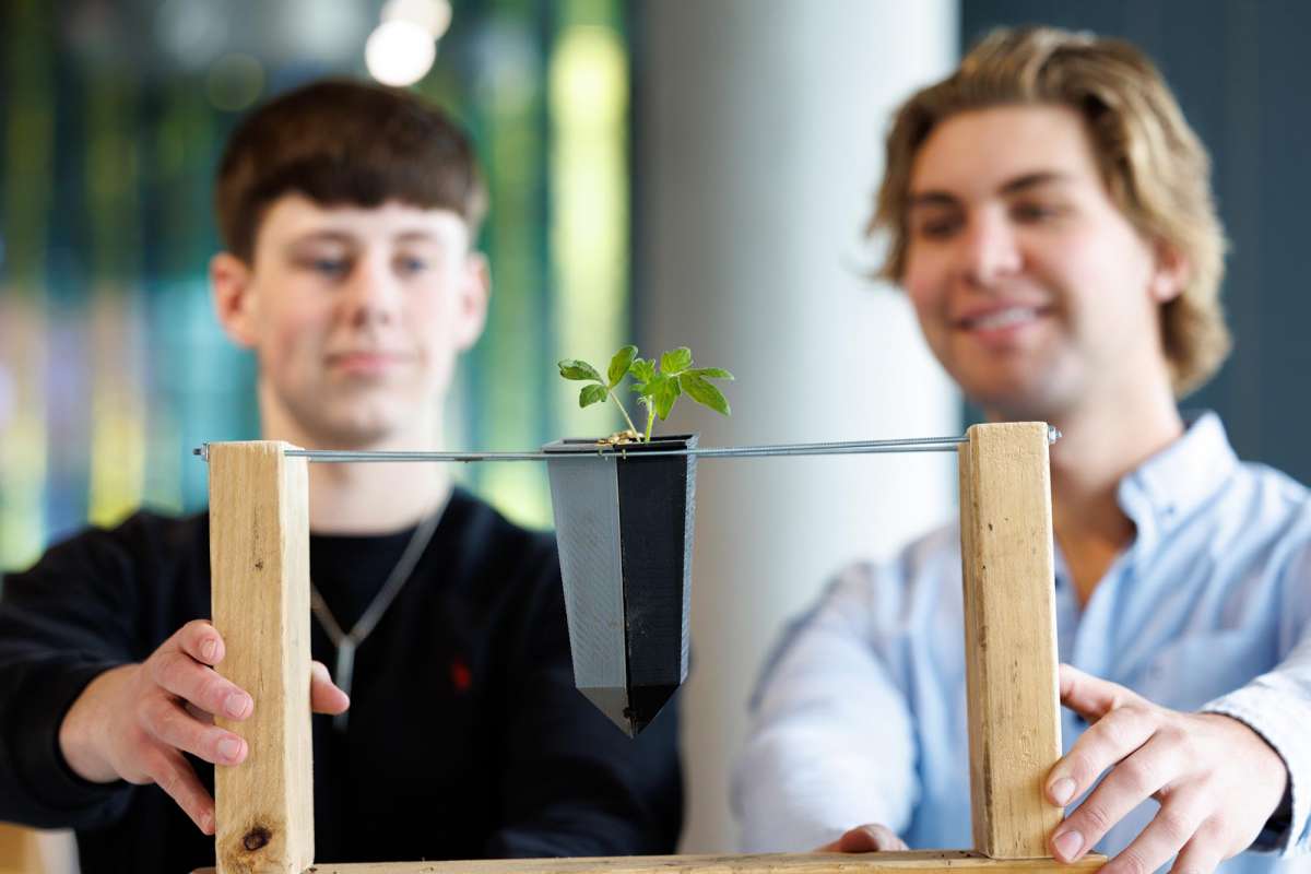Two students hold on to a small planting created as part of an innovation presentation