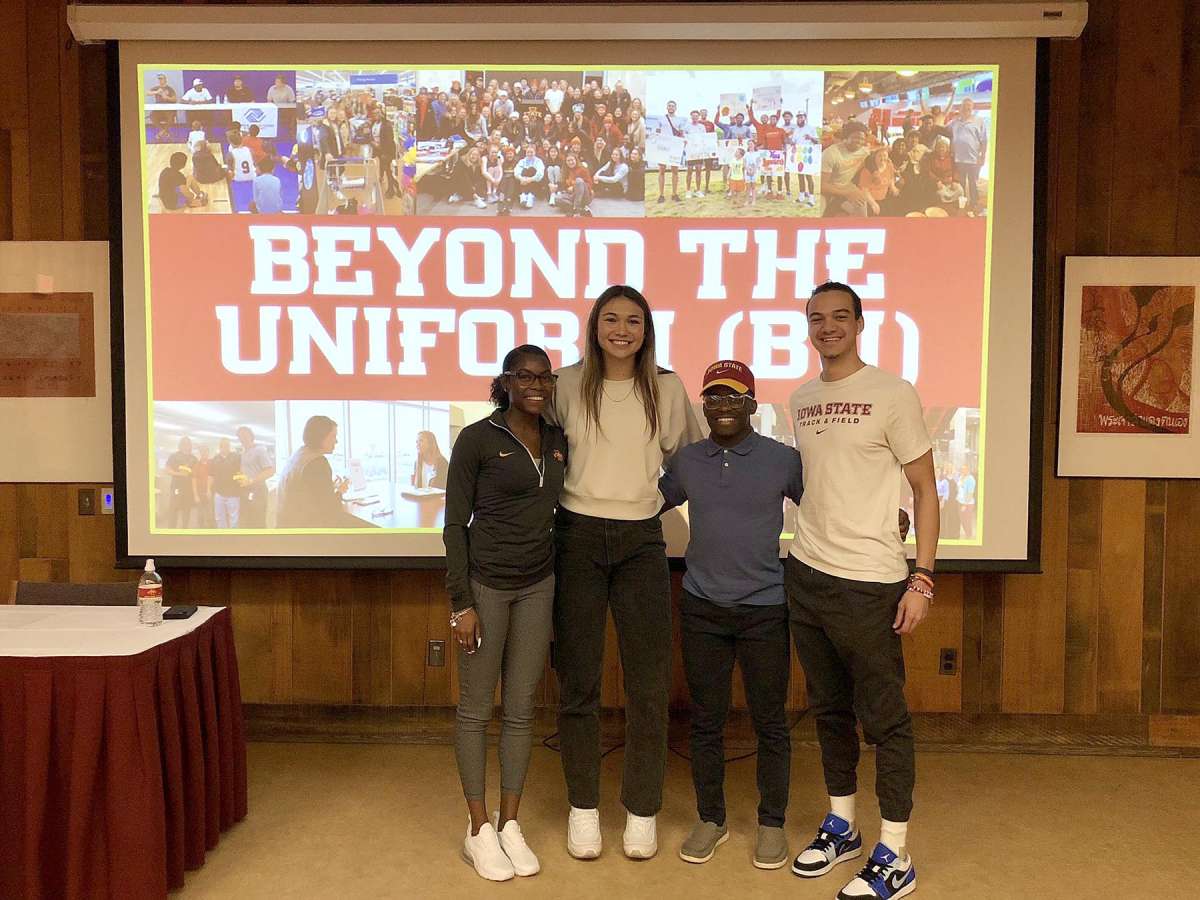 Four student-athletes pose in front of the screen for their ISCORE presentation