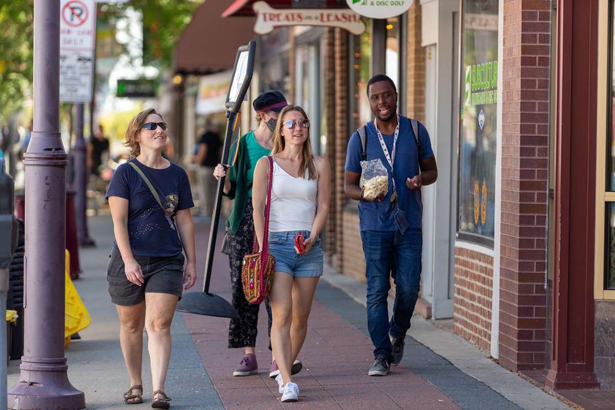 A group of smiling people walking on a downtown Ames sidewalk